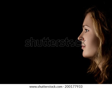profile of young pensive woman with red hairs on black background