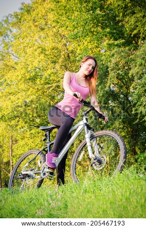 Young slim girl biking in evening park