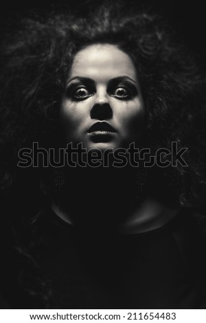 face of crazy woman with fluffy hair in dark monochrome image