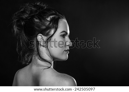 sensual young woman bare back profile in dark, monochrome image