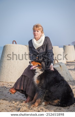 bernese mountain dog and woman sitting near sea