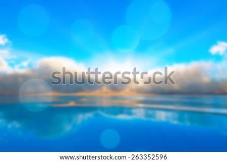 sun rays in clouds over tranquil ocean sunset blurred background