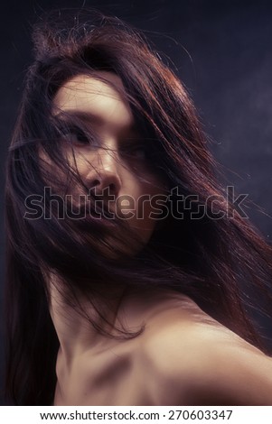 bared woman with fluffy hair looking back toned image