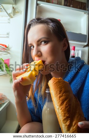 fun hungry woman eating food near refrigerator