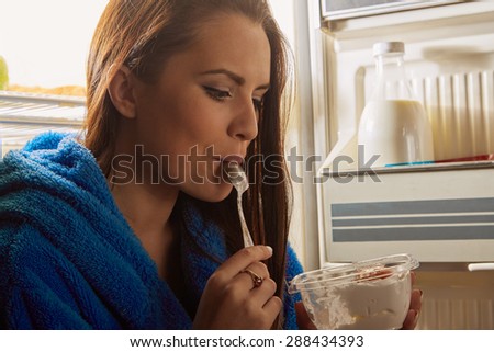woman eating dessert in refrigerator