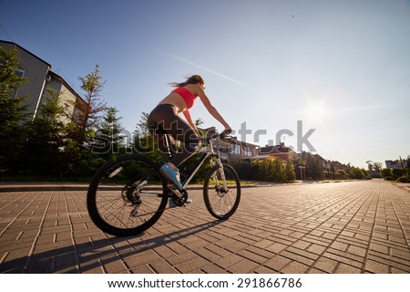 woman drives on bike in village at sunset, image with blur effect