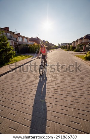 woman drives on bike in village at sunset