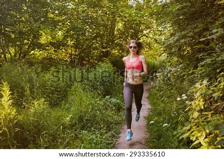 muscular woman running in sunny wood