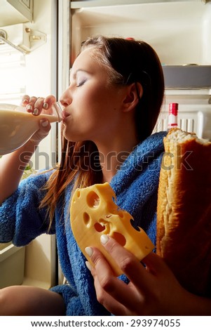 hungry woman drinking milk near refrigerator