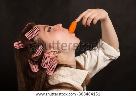 fun woman eating carrot on black background