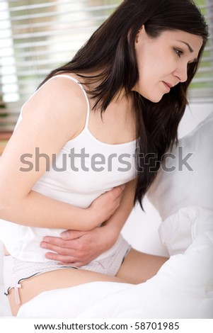 young adult brunette woman feeling pain in bed