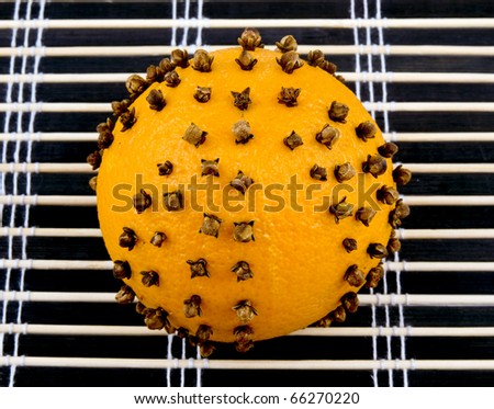 Aromatic orange with cloves on black bamboo mat background