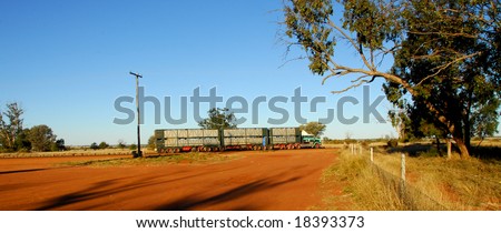 Road train in Australia crossing a outback country road with reddish or dusty scene