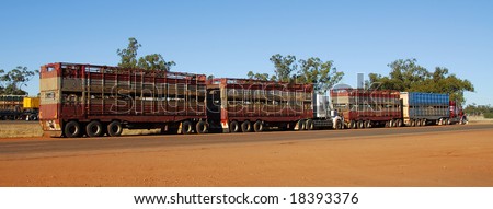 Road train in Australia crossing a outback country road with reddish or dusty scene