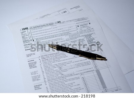 Pen on IRS forms 1040 and 1099. Shallow depth of field, focus on tip of the pen.
