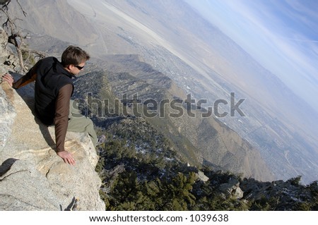 Young hiker man contemplating the breathtaking view atop summit. Amazing view of Joshua Tree National Park and Palm Springs, CALIFORNIA.