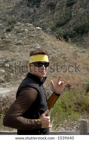 Young Man with Headscarf and Sunglasses smiling and making arm martial arts movements.