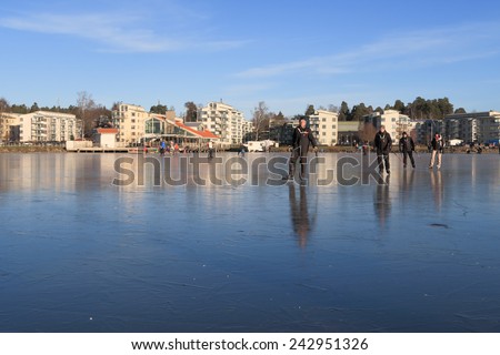 Vasteras, Sweden - January 4th: People Ice skating a cold sunny day on lake Malaren with Vasteras, Sweden, skyline in the background on January 4, 2015 in Vasteras, Sweden.