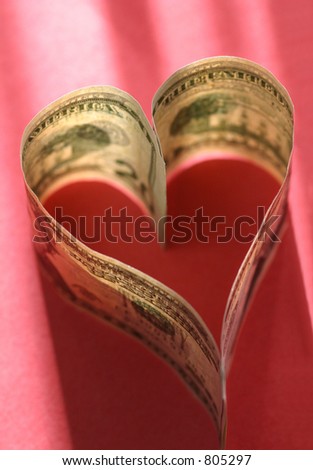 Love of Money:Two $20 bills form a heart, backlit on a red background.