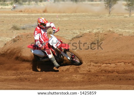 Removed all logos and numbers in this action shot of a motorbike taking a wide turn in a desert motor race. A competitor races to catch up in the background, kicking up dust along the way.