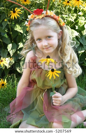 Sunshine Fairy:  A young, blonde woodland fairy stops to smell the  flowers in her outdoor setting.