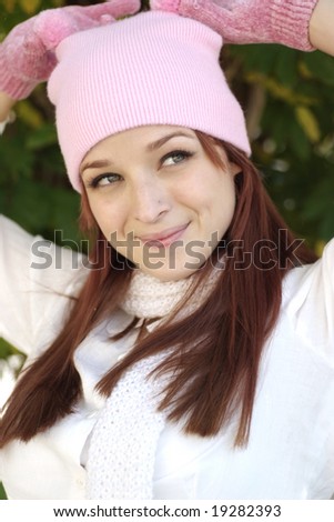 A beautiful woman with a red hair, white scarf, and pink bonnet and gloves.