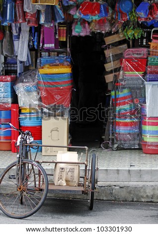 An old tricycle delivery transportation at a traditional sundry shop selling colorful household wares in Petaling Jaya, Malaysia.