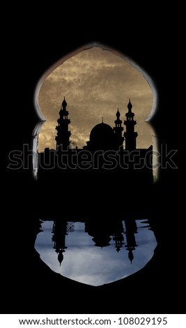 View of the silhouette of a muslim mosque over a surreal cloudy sky with reflection on a pool of water, through an islamic architectural arch.