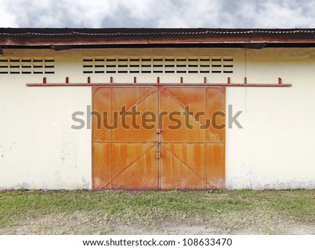 Facade of an old factory warehouse with a locked grungy metal sliding door.