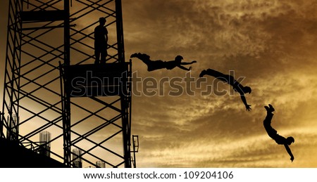 Silhouette of a boy diving off a scaffolding platform, against a surreal dramatic sunset sky, for the concept of urban extreme sports of parkour.