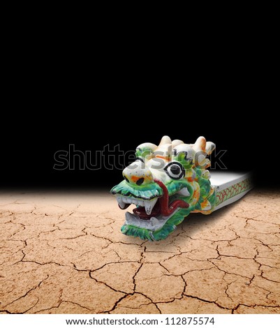 A creepy medieval dragon boat stranded on a dried up riverbed isolated against black.