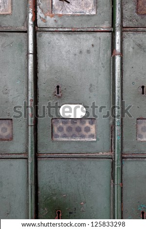Facade of an old aging metal postal box cabinet door with a blank label for text.