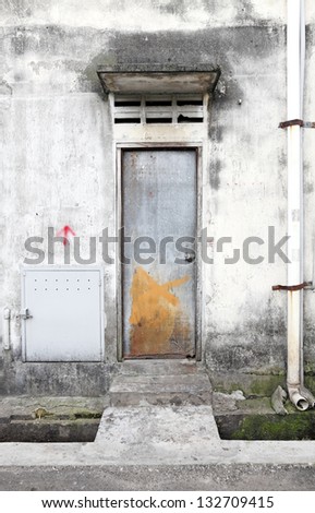 An exit metal backdoor on a dilapidated building in a grungy urban city backstreet.