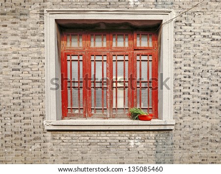 A vintage weathered timber window on a rustic clay brick building in the old city of Suzhou, China.