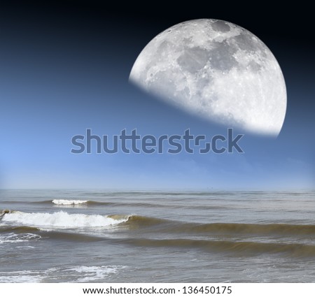 A moon rising from the horizon of an ocean with tidal waves. Elements of this image furnished by NASA.