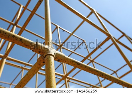 Closeup view of a yellow monkey bar metal frame in a children playground.