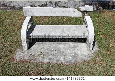 A damaged concrete bench in a park.