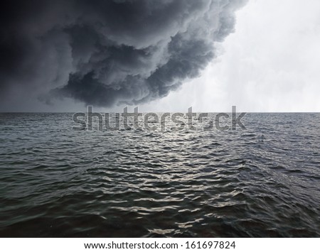 Dark stormy rain cloud in the horizon of a wavy sea.