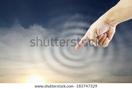 A human finger poking a surreal apocalyptic sunset sky causing a circular ripple.