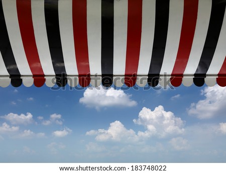 A retro stripe cafe canopy awning against a blue cloudy sky.
