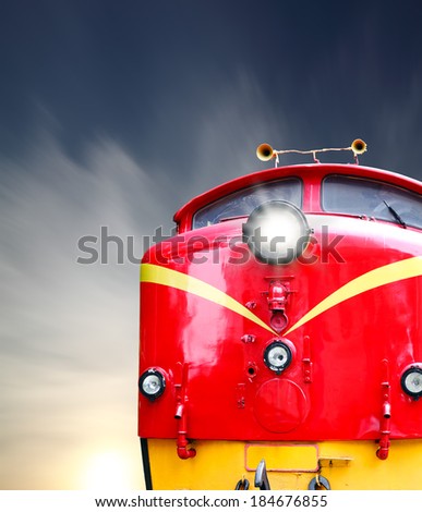 A red and yellow vintage diesel train head with a lighted head lamp.