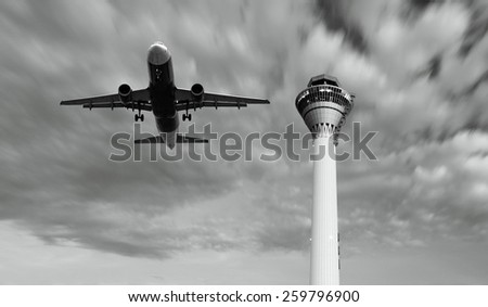An airplane taking off over an airport control tower.
