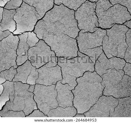 Surface of dried cracking parched earth, processed in monochrome, for textural background.