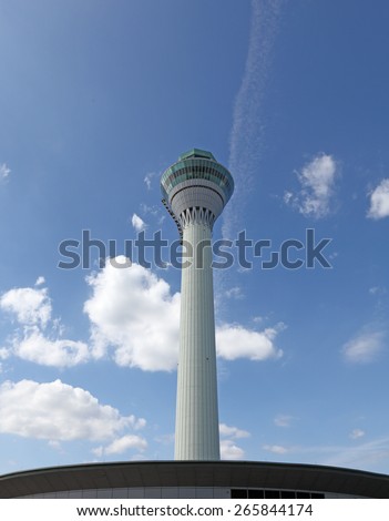 An airport air traffic control tower against a clear blue sky.