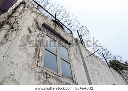 An old building wall surrounded by barbed wire.
