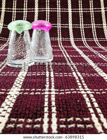 A salt and pepper shaker on a pattern picnic table cloth.