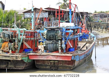 Two aging timber fishing trawler boat docked at the river side of a rural fishing village in Kuala Selangor, Malaysia.