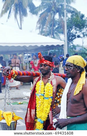 KUALA LUMPUR - JANUARY 20: Hindu devotee carrying heavy milk container on shoulder on Thaipusam festival on January 20, 2011 in Batu Cave as offering to Lord Murugan
