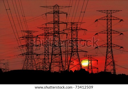 Electric power pylon congested on a hill against a surreal bloody red sunset.