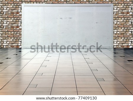 A blank white display board with space for text in a hall with brickwall in the background.